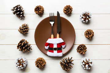 New Year set of plate and utensil on wooden background. Top view of holiday dinner decorated with pine cones. Christmas time concept