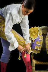 Woman bullfighter by dressing with vest on your back on a black background