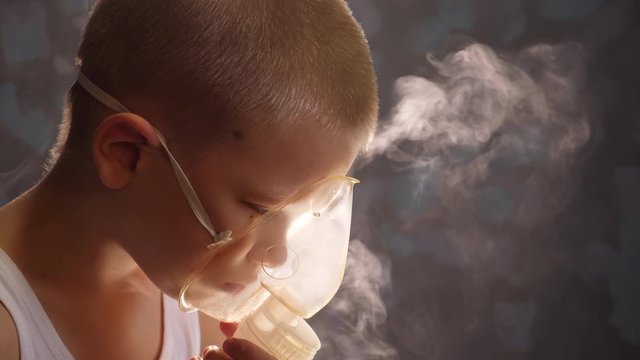 Caucasian blonde boy inhales couples containing medication to stop coughing. Medical procedures. Inhaler. Respiratory medicine. Bronchitis, asthmatic health equipment. Concept of home treatment