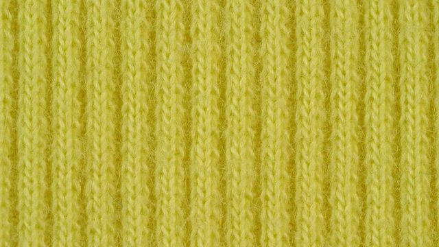 Textile background - light yellow cotton fabric with jersey (ribbing) structure. Weave pattern of threads close up. Macro shoot.