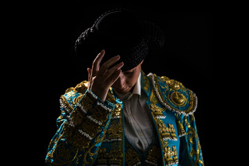 Woman bullfighter salutes with his montera in black background