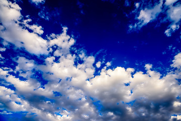 Beautiful puffy clouds with sun beams against blue skies.  