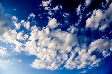 Beautiful puffy clouds with sun beams against blue skies.  