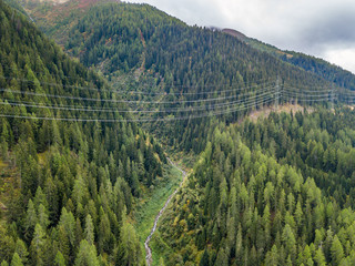 Aerial view of power line and pylon in alpine valley of Goms in Switzerland. Power grid through...