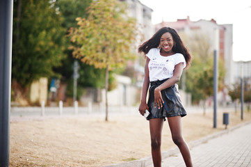 African american dark skinned slim model posed in a black leather shorts and white t-shirt.