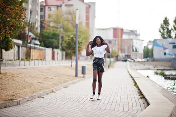 African american dark skinned slim model posed in a black leather shorts and white t-shirt.