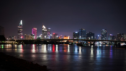 Fototapeta na wymiar Ho Chi Minh city night view at the bridge, river and skyscrapers. Saigon night life.Big city lights.