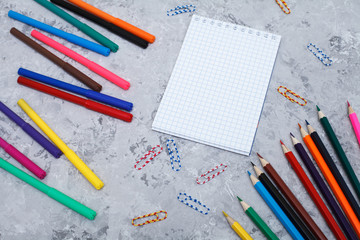 colored pencils, felt-tip pens, a white sheet and paper clips lie on a gray background, space for text. Top view, flat lay. template office accessories