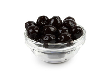Black olives in a glass saucer.