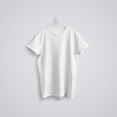 A blank T-shirt with shadows on a white plastic hanger  on a studio background.