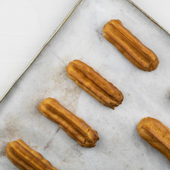 Freshly baked eclairs on a baking sheet.
