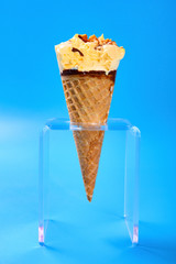 side view mango and chocolate flavor ice cream cone with peanut with a bite on blue background