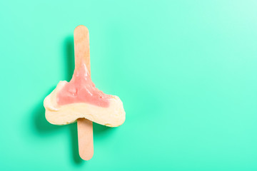 top view mostly eaten strawberry flavor popsicle on a green background