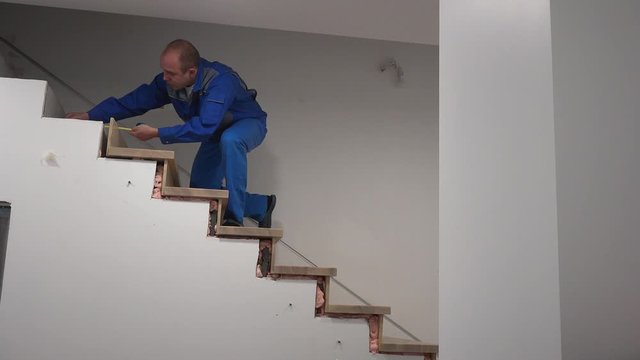 Carpenter man measure stair steps with meter tool. New staircase install works