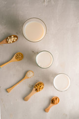 Fototapeta na wymiar Glasses of milk with nuts: Macadamia, almond, soy, rice, lotus. Top view.