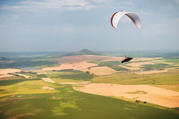 A paraglider flies in the sky in a cocoon suit on a paraglider over the Caucasian countryside with...
