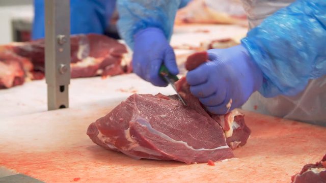 Butcher cutting beef by the conveyor belt
