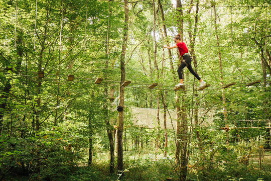 une femme en rouge dans la forêt fait de l'accrobranche dans les arbres