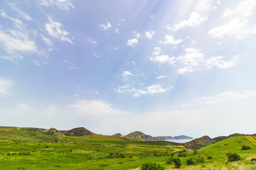 Fototapeta na wymiar Sunny weather over a field with hills near the sea