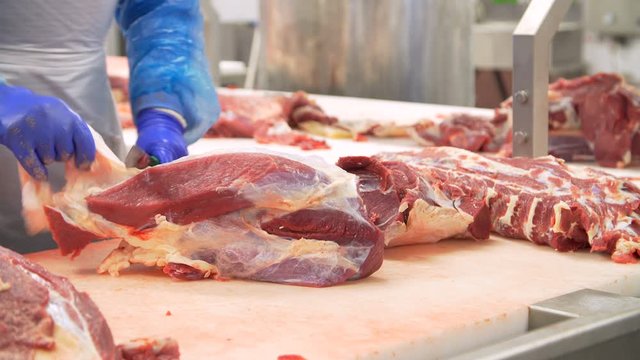 Butcher cutting beef by the conveyor belt