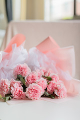 Pink bouquet of carnation flowers on the desk