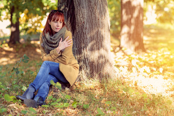Autumn trees, fall season. Fun in the autumn forest. Smiling ginger woman enjoying in nature.