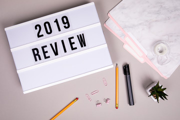 2019 review concept. White lightbox on a gray office desk