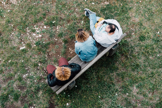 des gens assis sur un banc discutant. Discussion de trois personnes sur un banc. Un homme parle avec deux femmes. Des amis parlent.