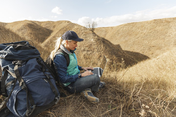 Naklejka na ściany i meble Traveler with backpack and laptop outdoor