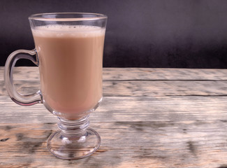 A cup of black coffee with milk standing on wooden background