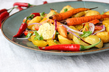 warm salad of baked potatoes and carrots with red onions, spices and tomatoes