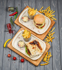 Fast food dish top view. Meat burger, potato chips and wedges. Take away composition. French fries, hamburger, mayonnaise and ketchup sauces on wood