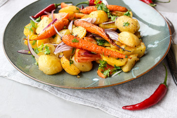 warm salad of baked potatoes and carrots with red onions, spices and tomatoes