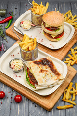 Fast food dish top view. Meat burger, potato chips and wedges. Take away composition. French fries, hamburger, mayonnaise and ketchup sauces on wood