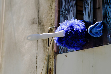 Blue Dustpan plugged on wooden fence at home.
