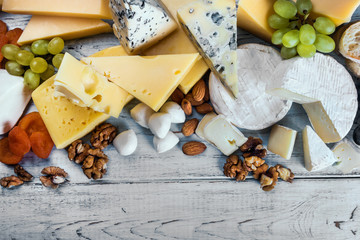 assorted different types of cheeses with fruits, nuts, dried fruits on the table