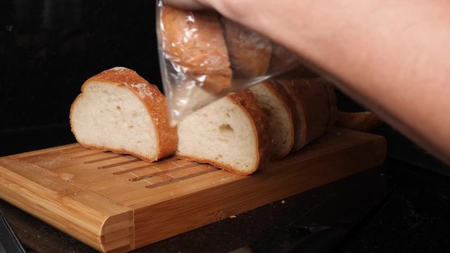 Shot of someone putting slices of fresh bread into individual plastic bags. 