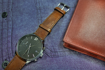 Men's accessories classic and luxury watch brown leather strap with wallet on blue jean shirt. for life stlye, elegant to dress of businessmen or casual stlye.