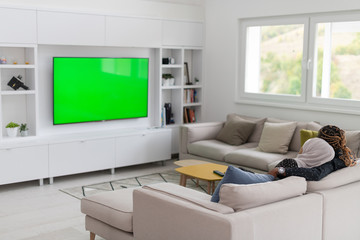 African Couple Sitting On Sofa Watching TV Together