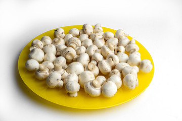 Heap of champignons on plate isolated on white background. Sliced mushrooms top view