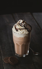 Delicious creamy milkshake with cookie on wooden table