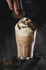 Delicious creamy milkshake with cookie on wooden table