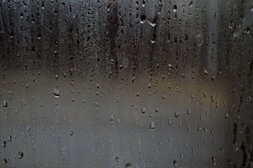Fog and raindrops on window glass, dark background and lantern l