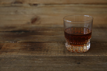 glass of whiskey or cognac or brandy on wooden rustic table with copy space for text