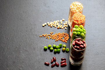 A selection of bean products for vegetarian dishes and more.  Beans, peas, fresh and dried, lentils.  They are rich in protein and useful elements.  Copy space.  Dark background.
