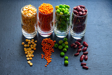 A selection of bean products for vegetarian dishes and more.  Beans, peas, fresh and dried, lentils.  They are rich in protein and useful elements.  Copy space.  Dark background.