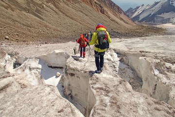 Alpinists mountaineers climbing over ice snow crevasse crack, extreme sport mountain climbing of...