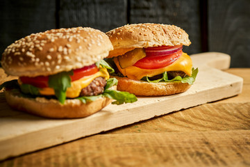Close up of tasty hamburger on wooden table and black background