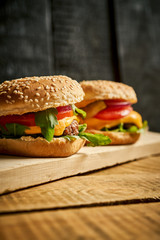 Close up of tasty hamburger on wooden table and black background