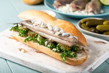 Traditional dutch snack, seafood sandwich with herring, onions and pickled cucumber. Broodje...